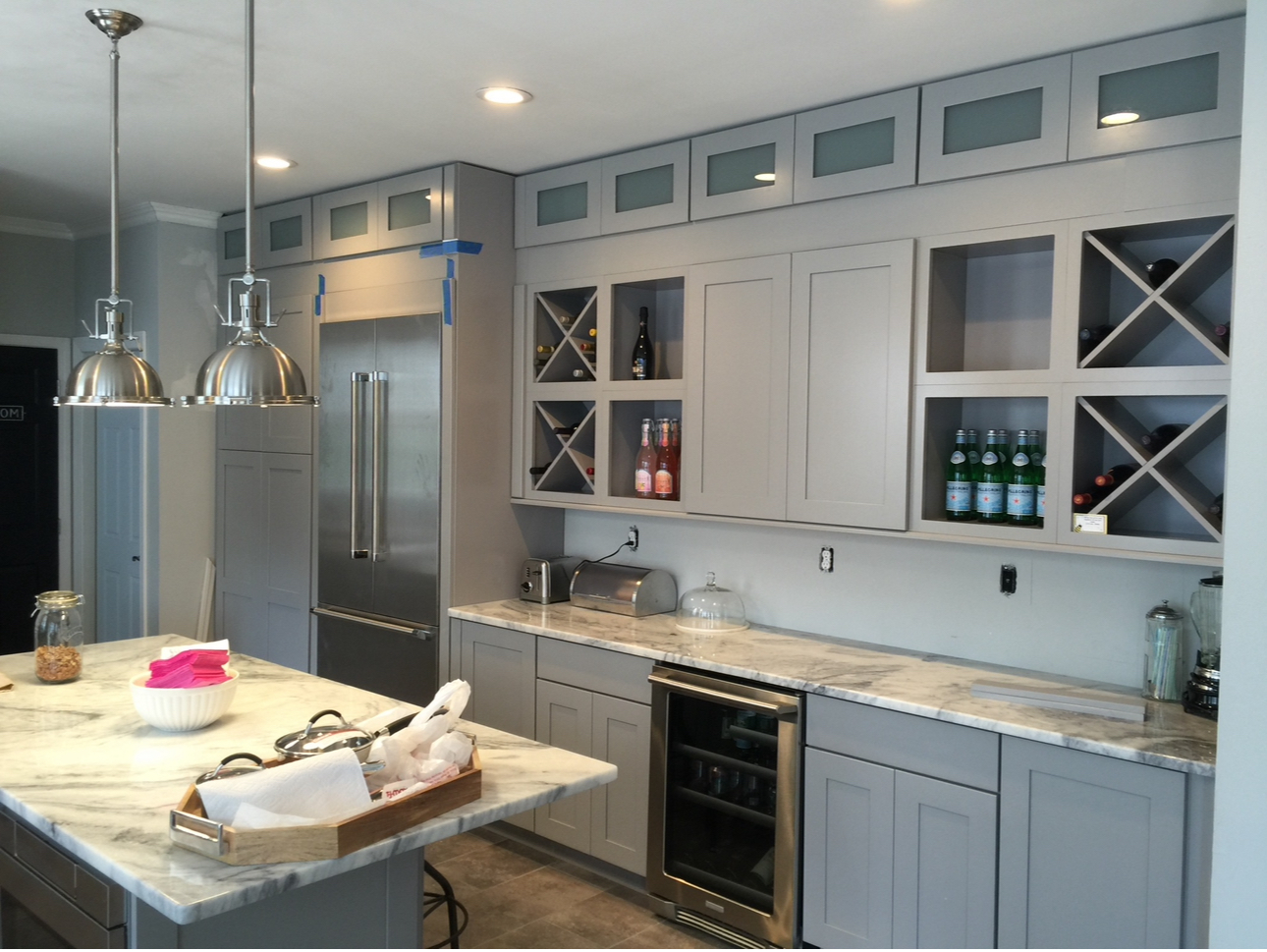 Modern kitchen with gray cabinets, marble countertops, and wine storage